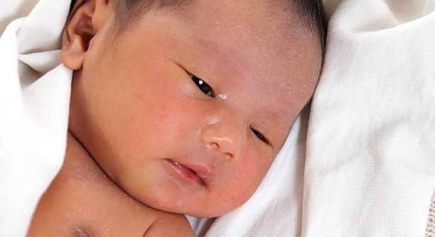 Cute newborn baby girl wrapped in white blanket